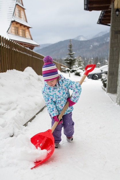 kleines Mädchen, das den Schnee vom Hof, Polen, Zakopane säubert