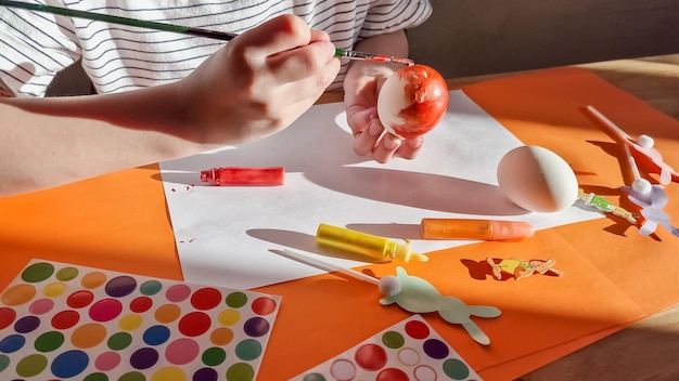 Kleines Mädchen, das Eier zu Ostern zu Hause im Kindergarten oder in der Vorschule malt. Feiertage mit Kindern feiern. Kreative Aktivitäten und Spiele für Kinder. Unterhaltung zu Hause bleiben