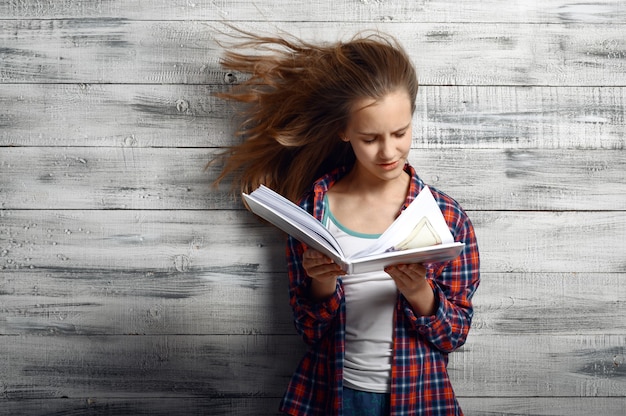 Foto kleines mädchen, das ein buch gegen starken luftstrom redet