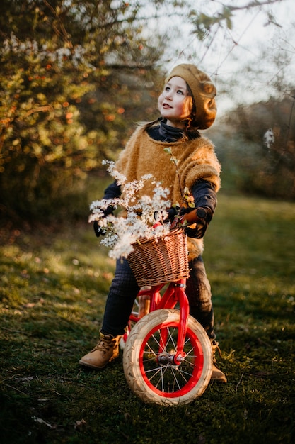 Kleines Mädchen, das ein frühes Fahrrad im Park im Frühjahr reitet