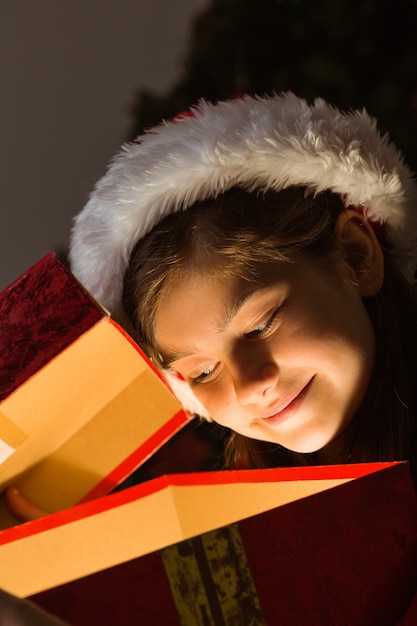 Kleines Mädchen, das ein magisches Weihnachtsgeschenk öffnet