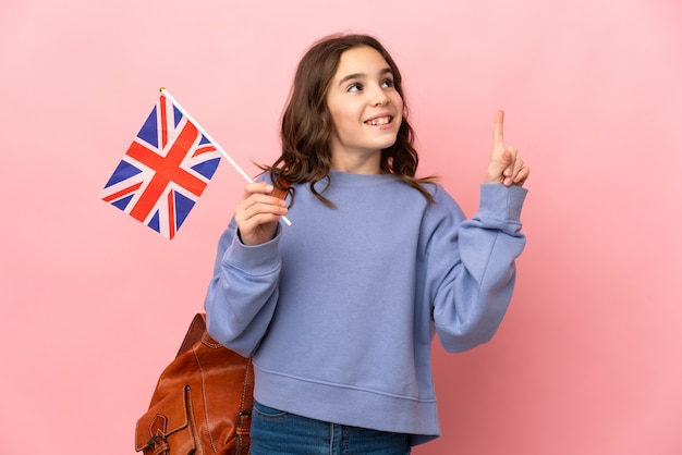 Kleines Mädchen, das eine britische Flagge lokalisiert auf rosa Hintergrund hält, der eine Idee denkt, die den Finger nach oben zeigt