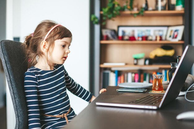 Kleines Mädchen, das einen Laptop verwendet