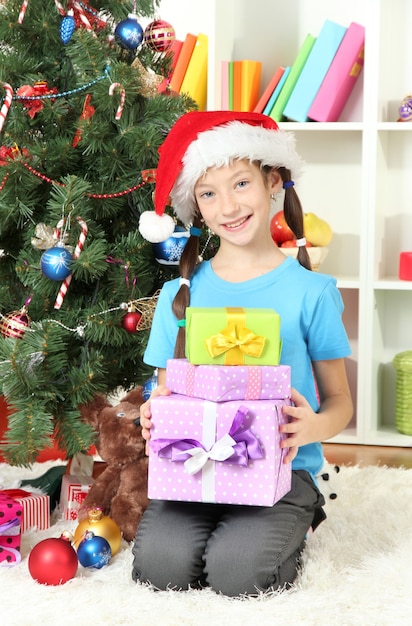 Kleines Mädchen, das Geschenkboxen nahe Weihnachtsbaum hält