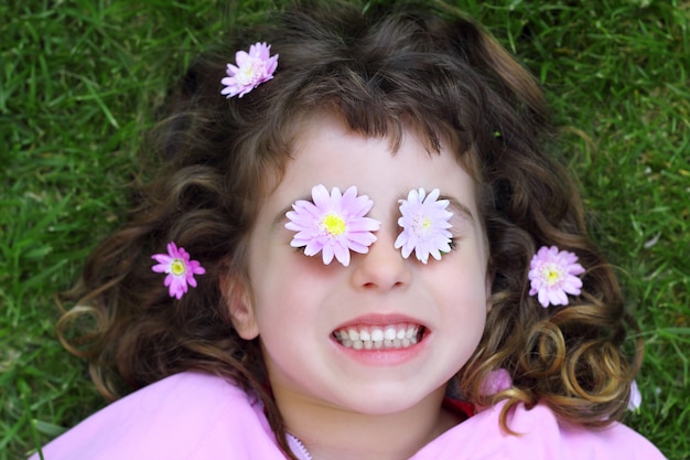 Kleines Mädchen, das Gras daisiy Blumen in Augen legt