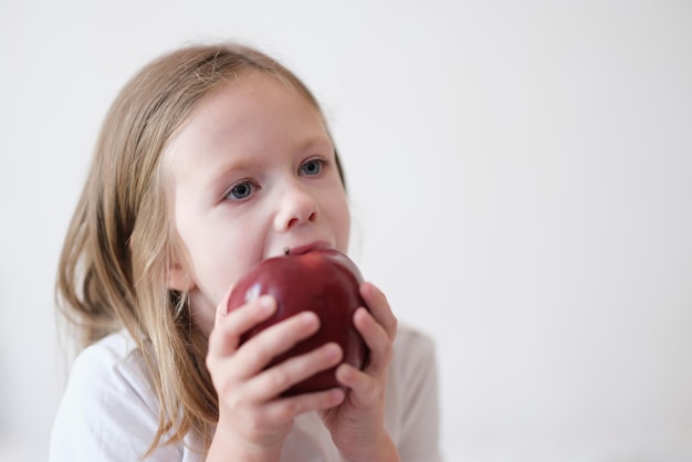Kleines Mädchen, das herzlich frischen roten Apfel isst