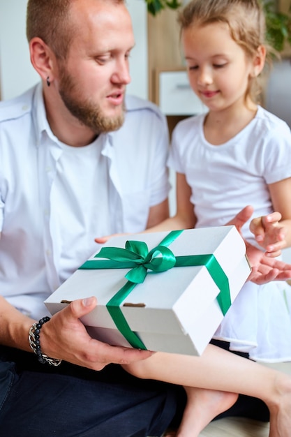 Kleines Mädchen, das ihrem hübschen Vater am Vatertag eine Geschenkbox gibt