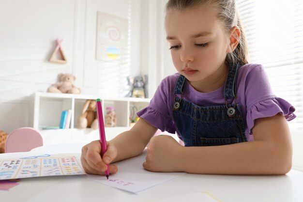 Kleines Mädchen, das im Englischunterricht Zahlen im Klassenzimmer schreibt