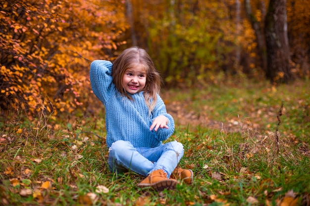 kleines Mädchen, das im Herbstwald in blauen Kleidern geht