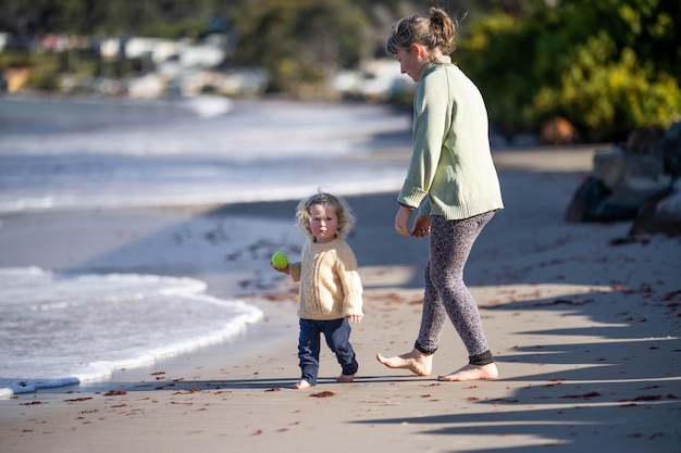 Kleines Mädchen, das im Sommer am Strand am Meer läuft