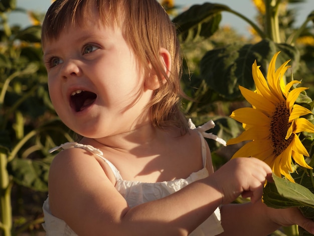 Kleines Mädchen, das im Sonnenblumenfeld spielt.