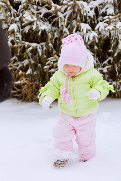 Kleines Mädchen, das im Winter mit Schnee spielt, Winteraktivitäten für Kinder