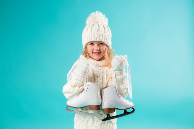 Kleines mädchen, das in einem weißen hut und in einer strickjacke des winters lächelt