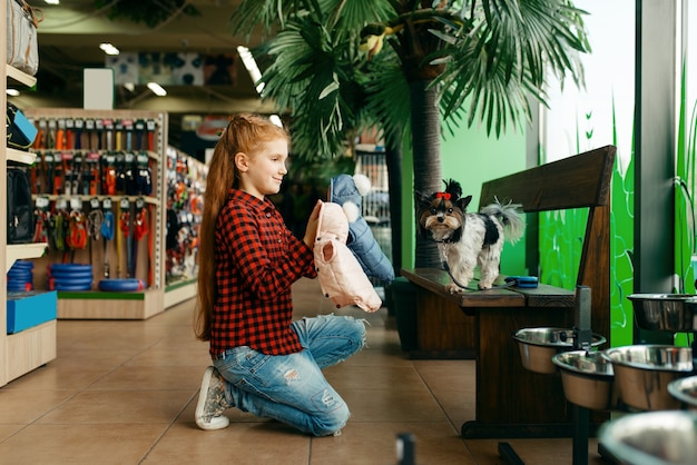 Kleines Mädchen, das Kleidung für ihren Hund in der Zoohandlung sucht. Kinderkaufausrüstung in der Zoohandlung, Zubehör für Haustiere