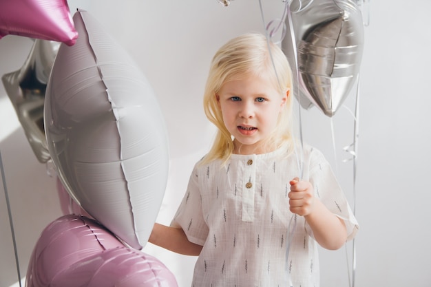 Kleines Mädchen, das Luftballons hält