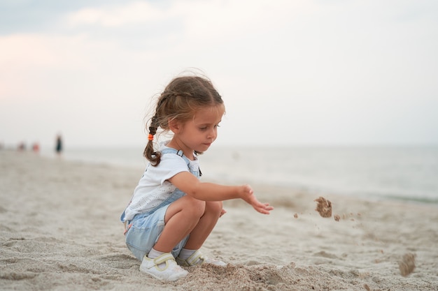 Kleines Mädchen, das mit dem Sand spielt