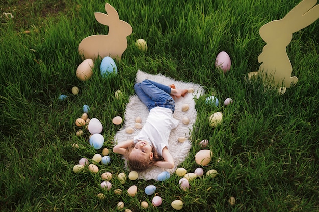 Kleines Mädchen, das mit Eiern an den Osterferien liegt