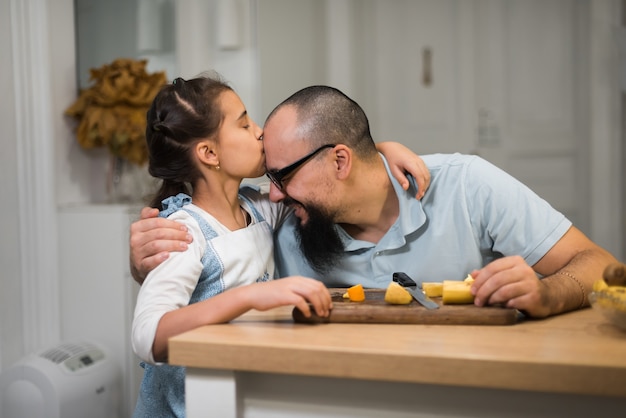 Kleines Mädchen, das mit einem liebevollen fürsorglichen Vater in einer modernen Küche kocht. Glücklicher junger Vater mit süßer Tochter in der Küche.