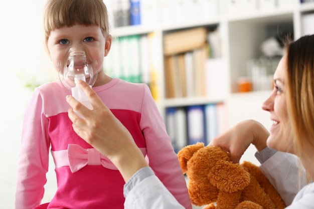 Kleines Mädchen, das mit Inhalator in der Arztpraxis atmet
