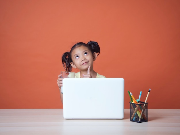 Kleines Mädchen, das mit Laptop studiert