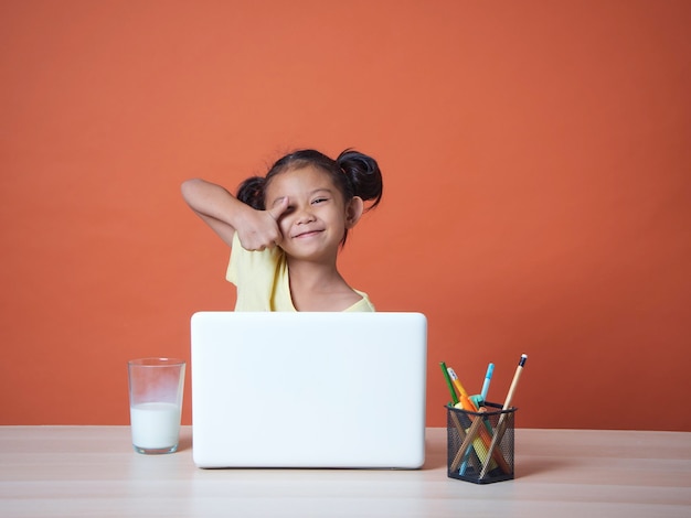 Kleines Mädchen, das mit Laptop studiert