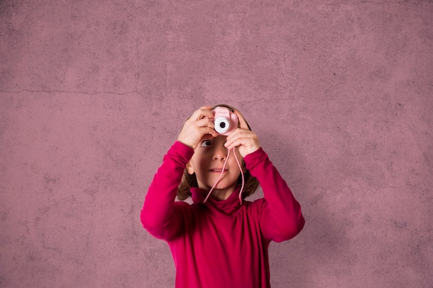 Kleines Mädchen, das mit Spielzeug-Fotokamera fotografiert