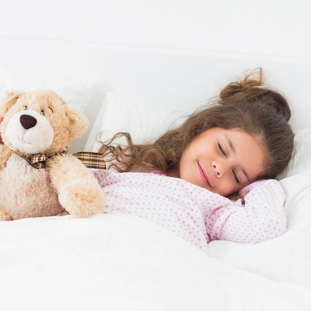 Kleines Mädchen, das mit Teddybären schläft