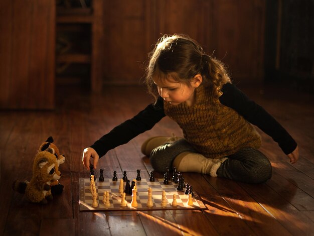 Kleines Mädchen, das Schach mit ihren Spielsachen spielt