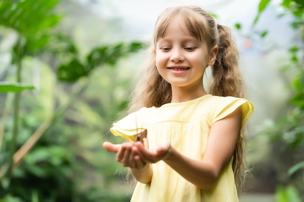 Kleines Mädchen, das Schmetterling in ihrer Hand hält.