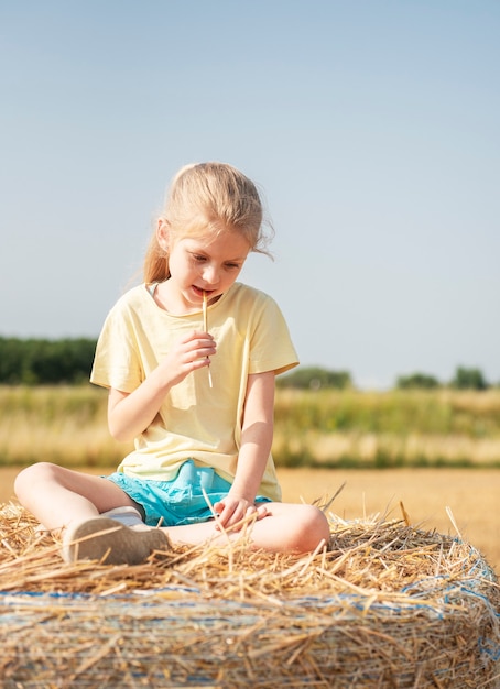 Kleines Mädchen, das sich an einem Sommertag auf einem Weizenfeld amüsiert