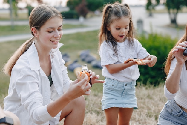 Kleines mädchen, das spaß am picknick mit pizza hat