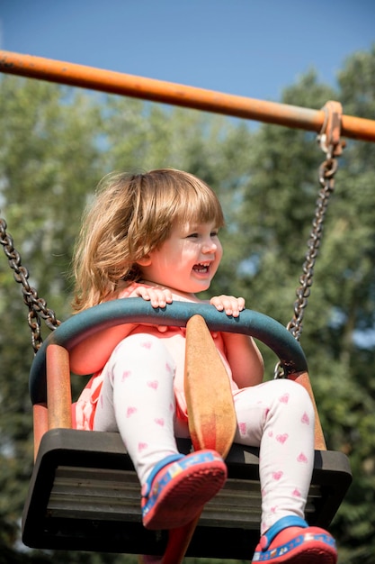Kleines Mädchen, das Spaß auf einer Schaukel im Freien hat Kleinkind Mädchen glückliches Kind