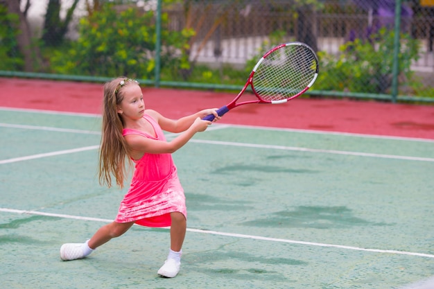 Kleines Mädchen, das Tennis auf dem Gericht spielt