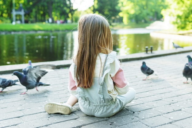 Kleines Mädchen, das Vögel in einem Stadtpark füttert