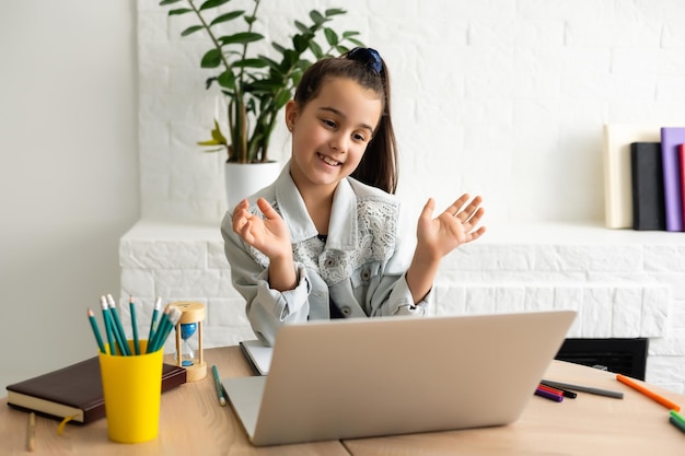 Kleines Mädchen, das von zu Hause aus an einer Online-E-Learning-Plattform teilnimmt, während die Schule während des Ausbruchs des Coronavirus geschlossen wurde.