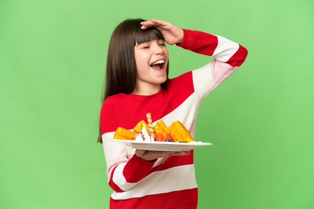 Kleines Mädchen, das Waffeln über isoliertem Chroma-Key-Hintergrund hält und viel lächelt