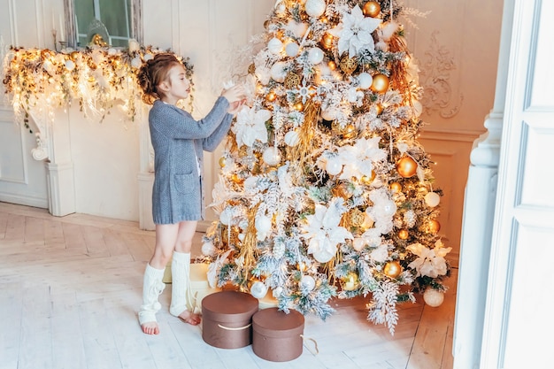 Kleines Mädchen, das Weihnachtsbaum zu Hause verziert