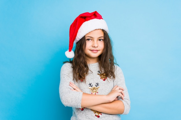 Kleines Mädchen, das Weihnachtstag feiert, der überzeugt sich fühlt und Arme mit Entschlossenheit kreuzt.