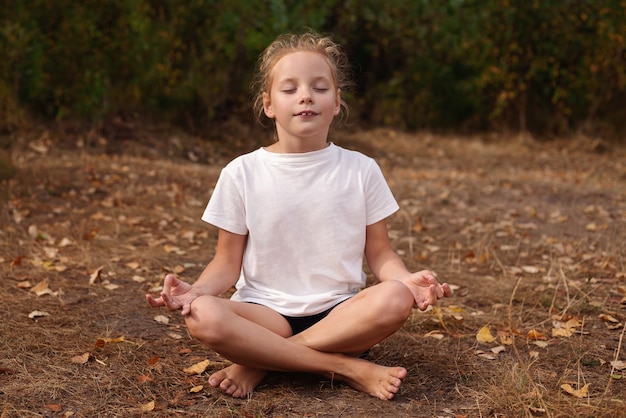 Kleines Mädchen, das Yoga auf dem Gras im Park tut