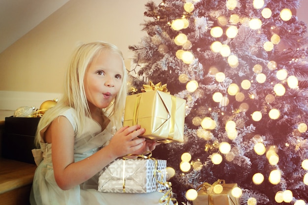 Kleines Mädchen, das zu Hause den Weihnachtsbaum schmückt