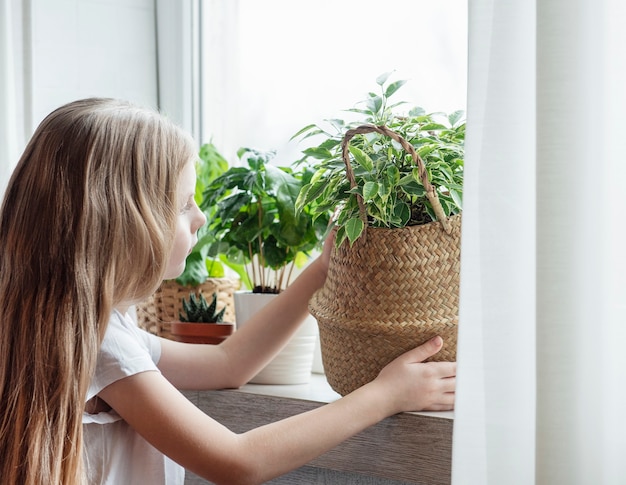 Kleines Mädchen, das zu Hause für Zimmerpflanzen sorgt