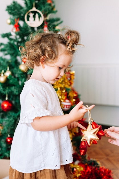 Kleines Mädchen decoratin Weihnachtsbaum mit Elternteil