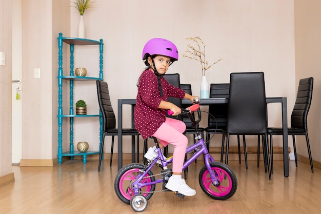 Kleines Mädchen fährt Fahrrad in ihrem Wohnzimmer