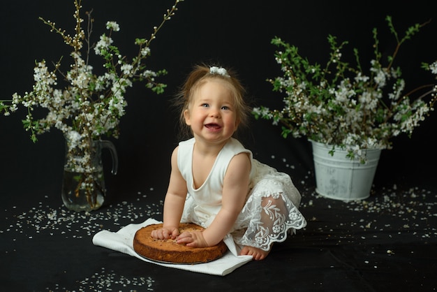 Kleines mädchen feiert ihren ersten geburtstag. mädchen, das ihren ersten kuchen isst.