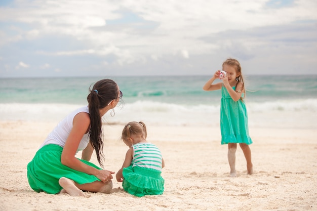 Kleines Mädchen fotografiert ihre Mutter mit Schwester am Strand