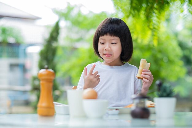 Kleines Mädchen frühstückt glücklich timexA