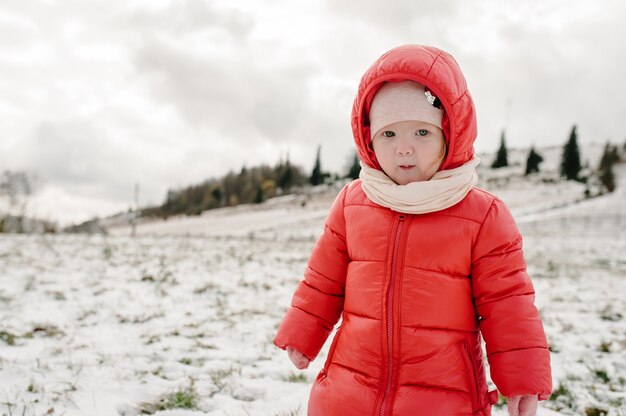 Kleines Mädchen gehen zurück auf schneebedeckten Berg, spielen auf Winternatur.