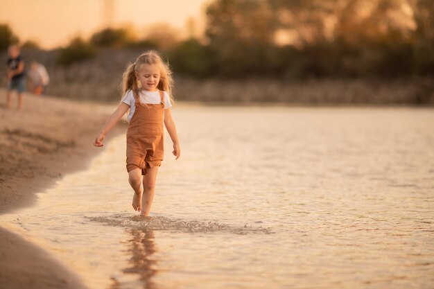 Kleines Mädchen geht entlang des Flusses Sommerurlaub Reisen Kinderfreizeit in der Natur Meer Fluss Sommer heißes Wetter kühlen Strand Spiele im Freien