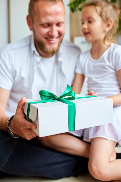 Kleines Mädchen gibt ihrem hübschen Vater am Vatertag eine Geschenkbox