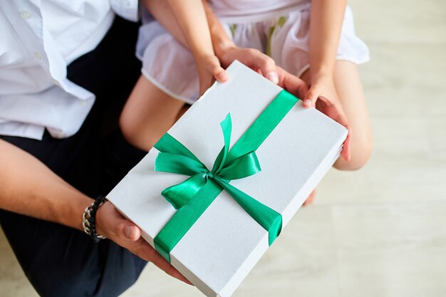 Kleines Mädchen gibt ihrem hübschen Vater am Vatertag eine Geschenkbox